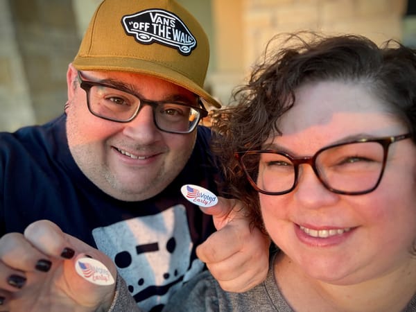 A man and a woman taking a selfie while holding up "I voted early" stickers.